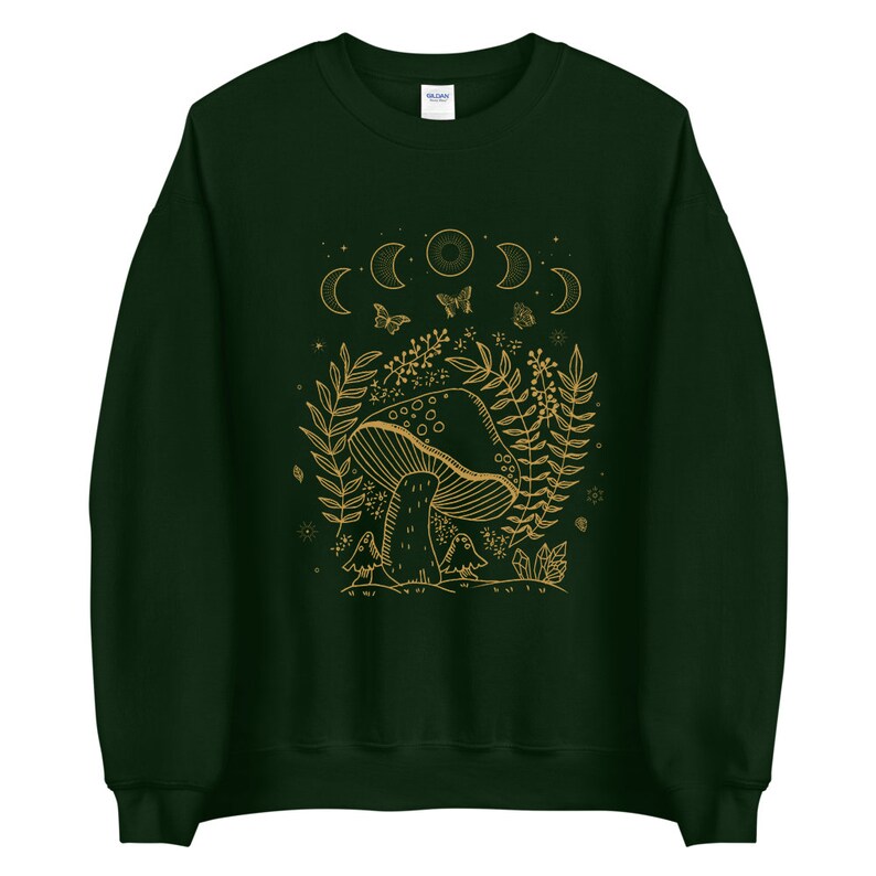 Op de afbeelding: Een donkergroen sweatshirt met een gouden omtrekillustratie van een paddenstoel, maanfasen, vlinders en bladeren.