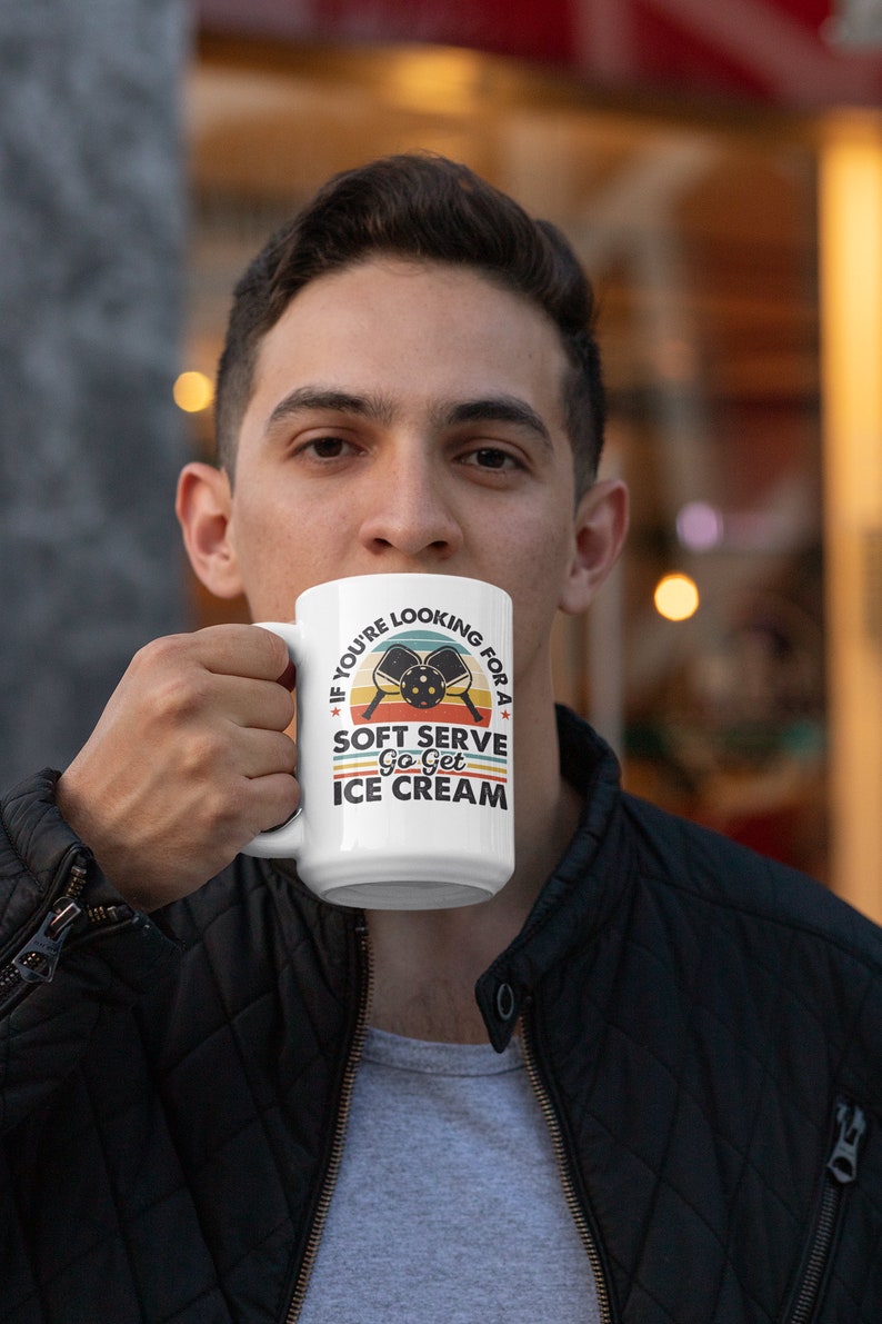 May include: White ceramic mug with a retro-style design featuring two pickleball paddles and the text "If you're looking for a soft serve, go get ice cream."