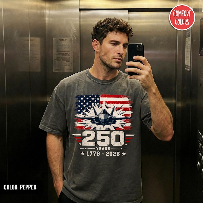 May include: Pepper-colored t-shirt featuring a graphic of an American flag with a jet fighter and the text "250 YEARS 1776-2026". The shirt is a Comfort Colors brand.