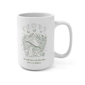 May include: White ceramic mug with a green line drawing of a mushroom, leaves, and butterflies. The moon phases are depicted above the mushroom. The text "We shall meet in the place where there is no darkness." is printed below the image.