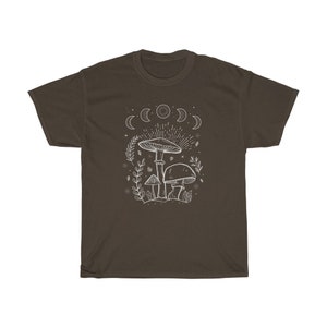 May include: A brown t-shirt featuring a white outline of mushrooms and a crescent moon design. The design depicts three mushrooms with a moon phase above them.