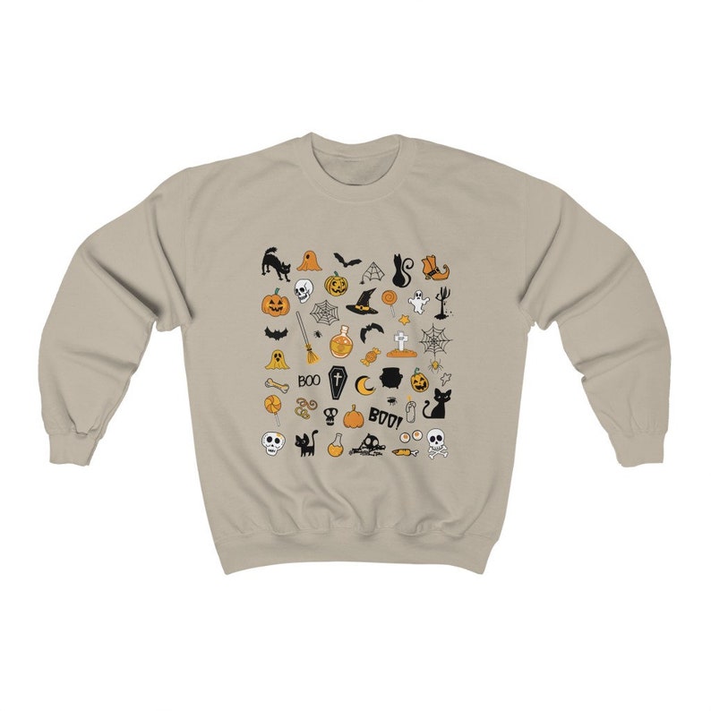 May include: A beige sweatshirt with a Halloween-themed design. The design features a variety of black and orange icons, including pumpkins, bats, ghosts, witches, and skulls.