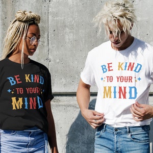 May include: Two people wearing black and white t-shirts with the text "Be Kind to Your Mind" in colorful letters. The text is surrounded by small stars.