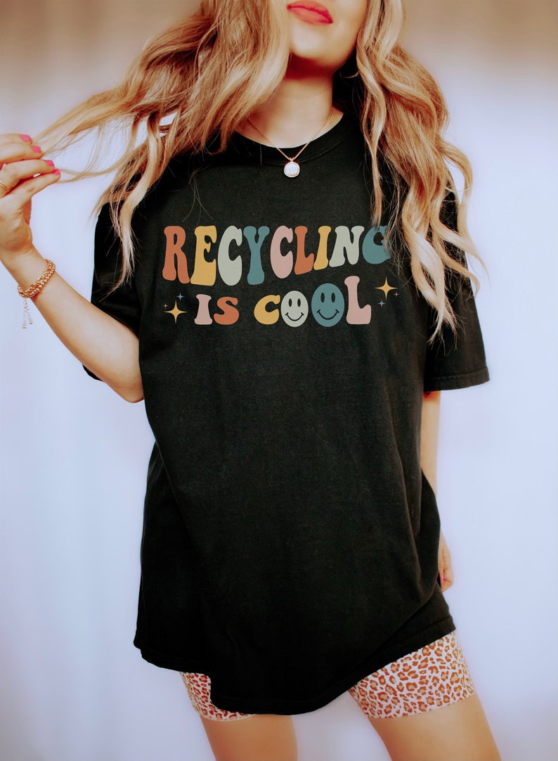 K&ouml;nnte beinhalten: Schwarzes T-Shirt mit dem Text "Recycling is Cool" in bunten Retro-Lettern und zwei Smiley-Gesichtern.