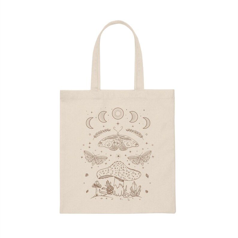 May include: A beige tote bag with a brown design featuring a mushroom, butterflies, and a crescent moon with stars.