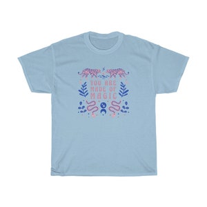May include: Light blue t-shirt with a pink and blue graphic design featuring tigers, snakes, and the text "You are made of magic".