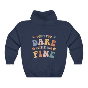 Puede incluir: Sudadera con capucha azul marino con el texto "Don't you dare settle for fine" en letras de colores con estrellas y flores.