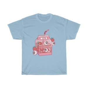 Puede incluir: Una camiseta azul claro con una ilustraci&oacute;n de dibujos animados rosa de una caja de leche con fresas y ojos. La caja dice "Pure Milk" en la parte superior.