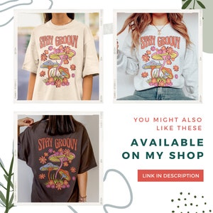 May include: A collection of t-shirts and a sweatshirt featuring a retro design. The design includes the text "STAY GROOVY" above a graphic of colorful mushrooms and flowers. The shirts are in cream, gray, and brown.