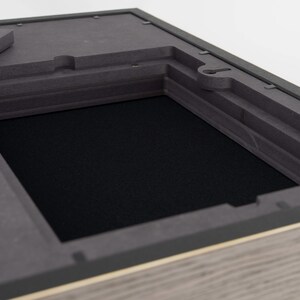 May include: A black wooden box with a hinged lid and a black foam interior. The box is open and the foam is visible.