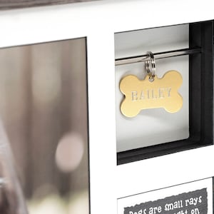 May include: A wooden picture frame with a black mat and a gold bone-shaped tag that says "BAILEY". The frame has a photo of a dog in it and a quote that says "Dogs are small rays of light on dark days".