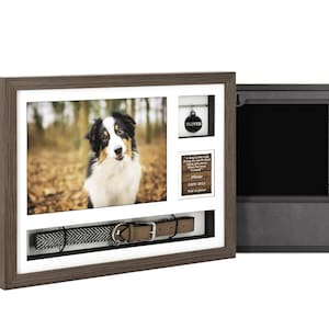 Pode incluir: Uma moldura de madeira marrom com um passe-partout branco e uma foto de um c&atilde;o preto e branco. A moldura tem um pequeno compartimento para uma etiqueta de cachorro e um compartimento maior para uma coleira de cachorro. A moldura est&aacute; aberta para revelar um compartimento forrado de veludo preto.