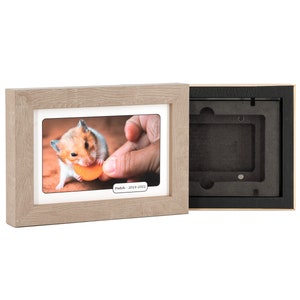 May include: A light wood picture frame with a white mat and a photo of a hamster eating a piece of orange food. The text "Panda - 2019-2023" is printed below the photo.