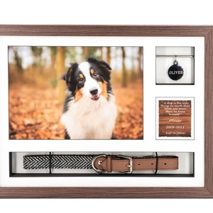 Pode incluir: Uma moldura de madeira castanho com um passe-partout branco cont&eacute;m uma foto de um c&atilde;o preto e branco, uma etiqueta de identifica&ccedil;&atilde;o para c&atilde;es com o nome "Oliver", uma pequena placa de madeira com uma citaat sobre c&atilde;es e uma coleira de c&atilde;o com padr&atilde;o preto e branco com uma fivela de couro castanho.