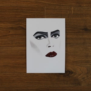 Puede incluir: Una ilustraci&oacute;n en blanco y negro de un rostro con sombra de ojos oscura y l&aacute;piz labial rojo.