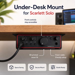May include: A black and red Scarlett Solo audio interface mounted under a wooden desk. The text "Under-Desk Mount for Scarlett Solo" is visible. Features include space saving, secure mount, and studio ready.