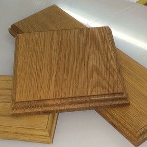May include: Close-up of several unfinished oak wood pieces. The pieces are various sizes and shapes, including a square and rectangular pieces. The wood grain is visible, and the pieces have a natural, light brown colour. These pieces could be used for woodworking projects.