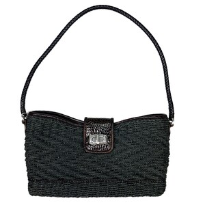 Puede incluir: Un bolso tejido negro con una solapa de cuero marr&oacute;n y un cierre plateado. El bolso tiene una sola correa.