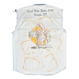 May include: White sleeveless denim vest with a faded yellow and orange graphic of a Native American woman riding a wolf. The vest has the text "Black Hills Rally 2000 Sturgis, SD" printed on the back.
