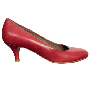May include: A pair of red leather heeled pumps with a low heel.