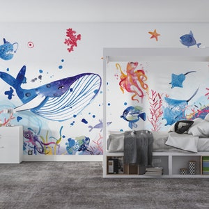 Ocean wallpaper featuring a whimsical underwater scene with a smiling whale, playful octopus, gliding starfish, and various fish among coral reefs, perfect for a nursery or playroom.