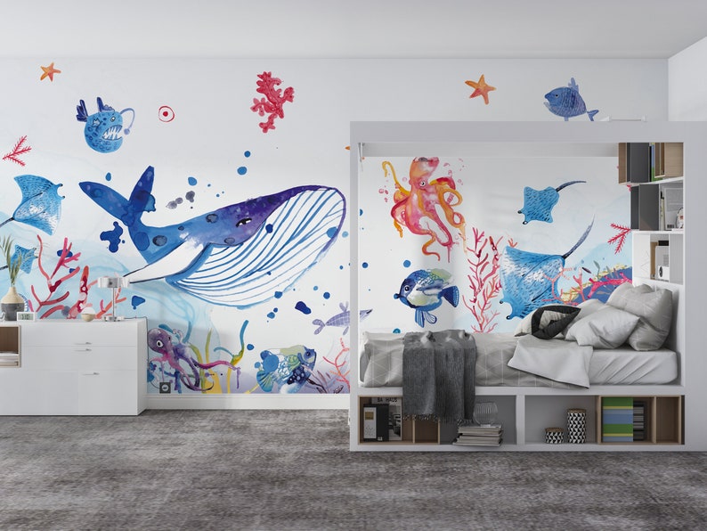 Ocean wallpaper featuring a whimsical underwater scene with a smiling whale, playful octopus, gliding starfish, and various fish among coral reefs, perfect for a nursery or playroom.