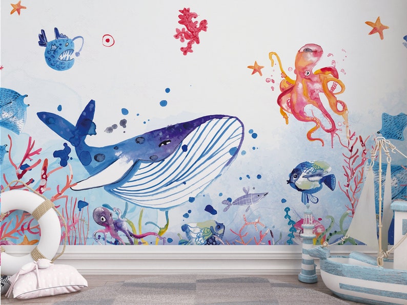 Ocean wallpaper featuring a whimsical underwater scene with a smiling whale, playful octopus, gliding starfish, and various fish among coral reefs, perfect for a nursery or playroom.