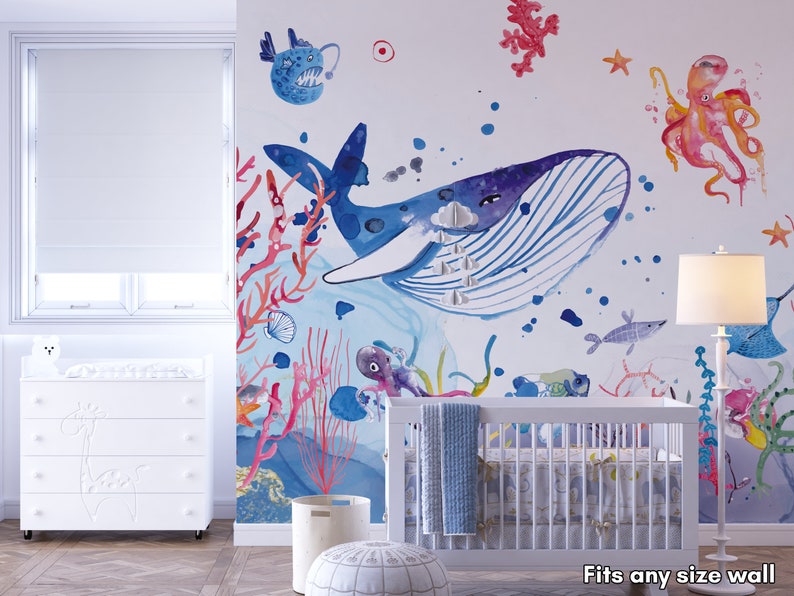 Ocean wallpaper featuring a whimsical underwater scene with a smiling whale, playful octopus, gliding starfish, and various fish among coral reefs, perfect for a nursery or playroom.