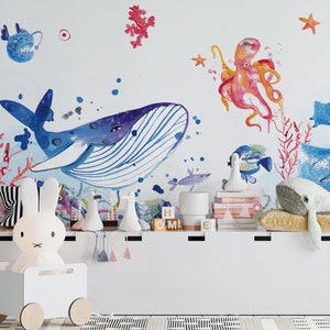 Ocean wallpaper featuring a whimsical underwater scene with a smiling whale, playful octopus, gliding starfish, and various fish among coral reefs, perfect for a nursery or playroom.