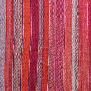 Puede incluir: Primer plano de una tela tejida con un patrón de rayas en tonos rojos, rosas y blancos.