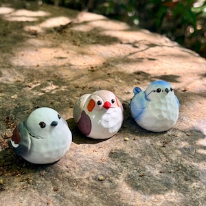 May include: A set of three ceramic mugs with a speckled, matte finish in cream, light grey, and dark grey. Each mug has a simple, minimalist design and a rounded handle.