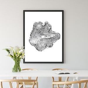 May include: A black and white print of a tree trunk cross-section, framed in black, hangs on a white wall above a white table with four wooden chairs.