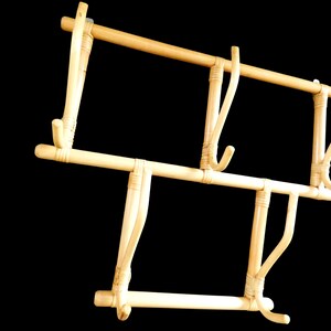 Puede incluir: Un perchero de bamb&uacute; natural con cuatro ganchos. El perchero est&aacute; hecho de bamb&uacute; marr&oacute;n claro y tiene un dise&ntilde;o simple y r&uacute;stico.