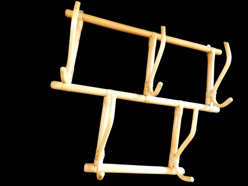 Puede incluir: Un perchero de bamb&uacute; natural con cuatro ganchos. El perchero est&aacute; hecho de bamb&uacute; marr&oacute;n claro y tiene un dise&ntilde;o simple y r&uacute;stico.