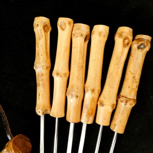 May include: Set of six bamboo skewers with metal tips. The skewers are natural brown and have a smooth finish.
