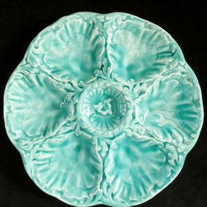 Può includere: Un piatto per ostriche in ceramica blu turchese con cinque sezioni di servizio individuali. Il piatto è decorato con dettagli in rilievo a forma di conchiglia.