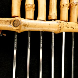May include: A set of six bamboo skewers with stainless steel tips. The skewers are tied together with a brown leather cord. The tips are marked "Stainless Steel Japan".