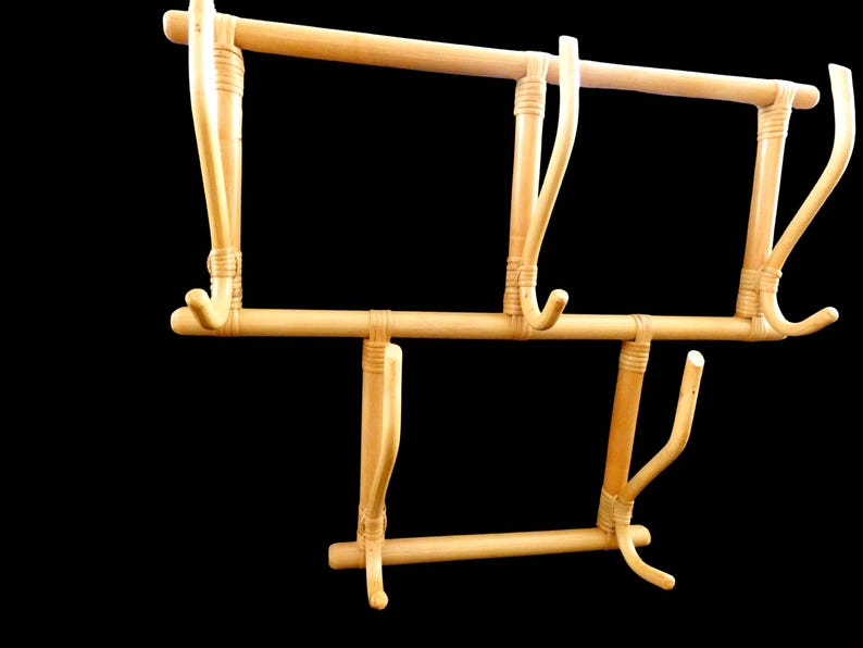 Puede incluir: Un perchero de madera con cinco ganchos. El perchero est&aacute; hecho de bamb&uacute; natural y tiene un color marr&oacute;n claro.