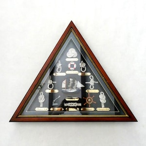 Puede incluir: Una vitrina triangular de madera con frente de cristal que contiene una colección de nudos marinos de cuerda blanca sobre un fondo negro. Cada nudo está etiquetado con una pequeña placa dorada y se incluye una ilustración de un barco.