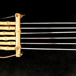 May include: A set of six metal skewers with wooden handles. The skewers are attached to a wooden base with a leather strap.