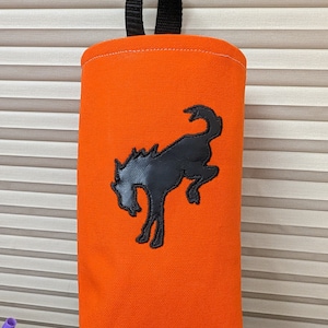 May include: Orange canvas bag with a black handle and a black embroidered silhouette of a bucking horse.