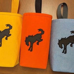 May include: Five fabric pouches with a black horse silhouette design. The pouches are in pink, yellow, orange, light blue, and black. Each pouch has a black loop handle.