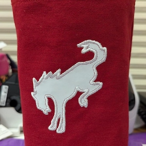 May include: Red canvas tote bag with a white embroidered horse head design. The bag has a black handle.