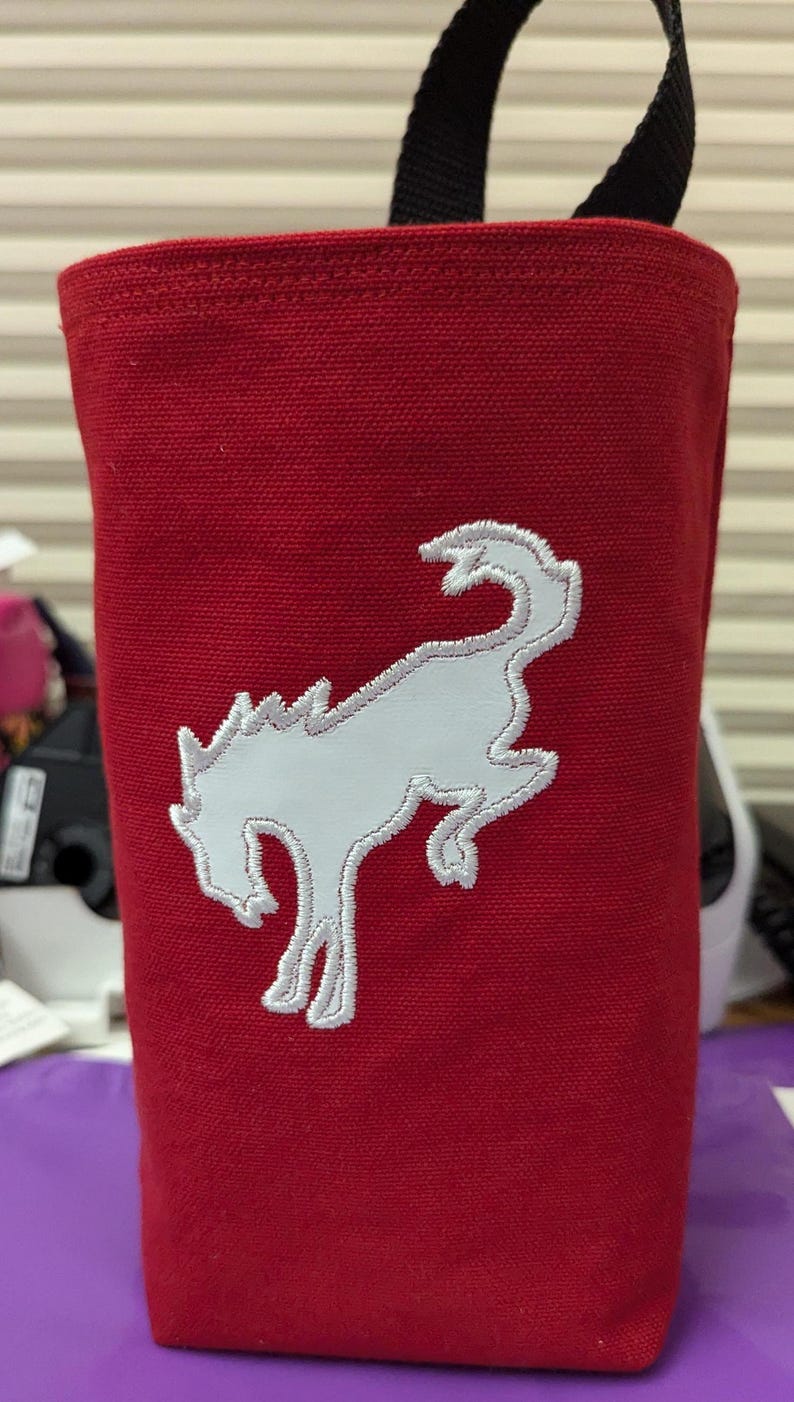 May include: Red canvas tote bag with a white embroidered horse head design. The bag has a black handle.