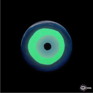 May include: A blue and white evil eye charm with a green center. The eye is a popular symbol of protection against bad luck.