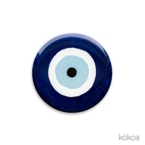 Op de afbeelding: Een blauwe en witte boze oog charme met een zwarte pupil. De charme is rond en heeft een glanzende afwerking.