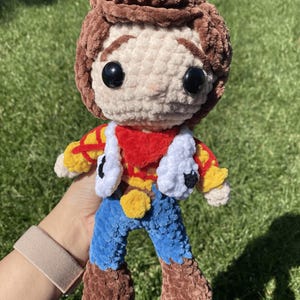 Puede incluir: Mu&ntilde;eca de ganchillo hecha a mano que se asemeja a un personaje de una popular pel&iacute;cula de animaci&oacute;n. La mu&ntilde;eca presenta cabello casta&ntilde;o, una cara color crema y un atuendo rojo, amarillo y azul. La mu&ntilde;eca mide aproximadamente 20 cm de altura.