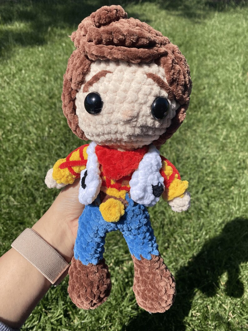 Puede incluir: Mu&ntilde;eca de ganchillo hecha a mano que se asemeja a un personaje de una popular pel&iacute;cula de animaci&oacute;n. La mu&ntilde;eca presenta cabello casta&ntilde;o, una cara color crema y un atuendo rojo, amarillo y azul. La mu&ntilde;eca mide aproximadamente 20 cm de altura.