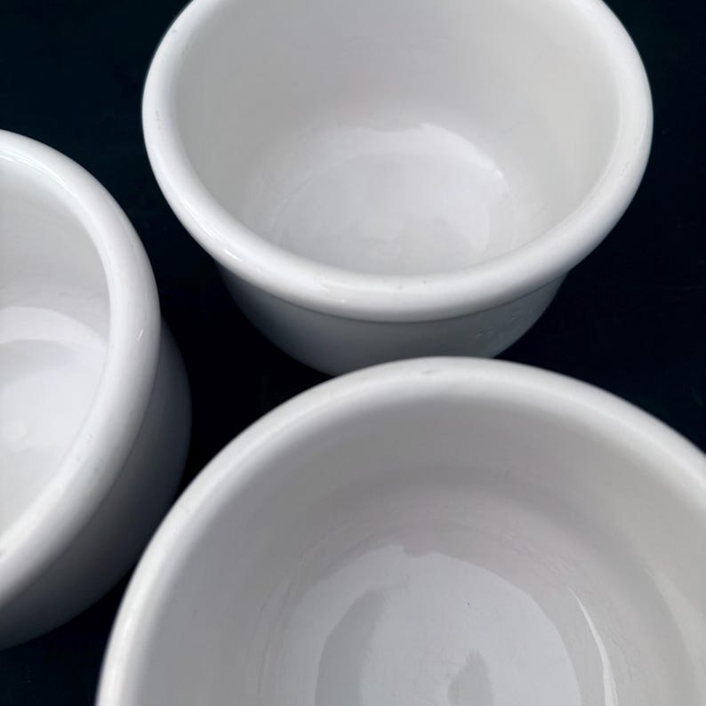 Puede incluir: Primer plano de tres cuencos peque&ntilde;os de cer&aacute;mica blanca. Los cuencos tienen un dise&ntilde;o simple y redondeado con un acabado liso y brillante. Est&aacute;n vac&iacute;os y limpios, lo que sugiere que est&aacute;n listos para usar. Ideal para servir.
