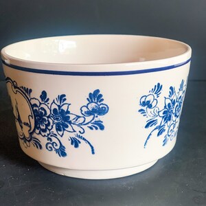 Puede incluir: Cuenco de cer&aacute;mica blanca con motivos florales azules. El cuenco tiene un borde azul y una base de pedestal. El dise&ntilde;o floral incluye flores y hojas estilizadas. El cuenco es probablemente para servir o exhibir.